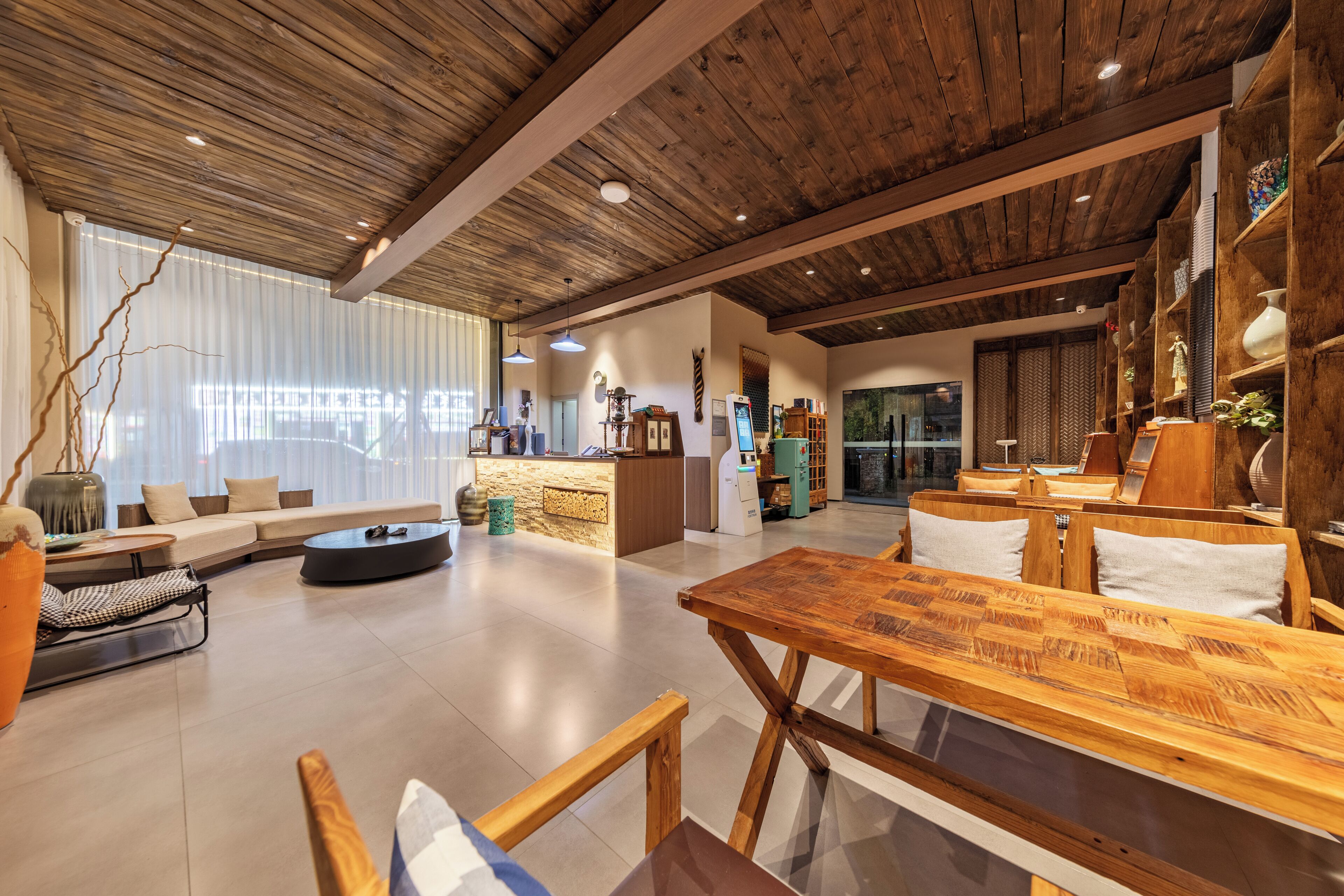 Amplia sala de estar con mesa de comedor de madera, un sofá y zona de cocina al fondo.