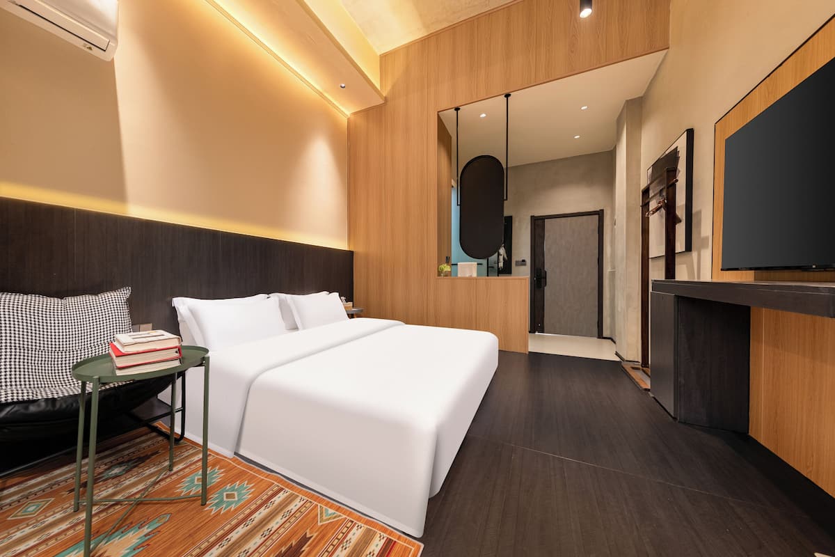 A modern hotel room with a bed, bedside table, and a TV.
