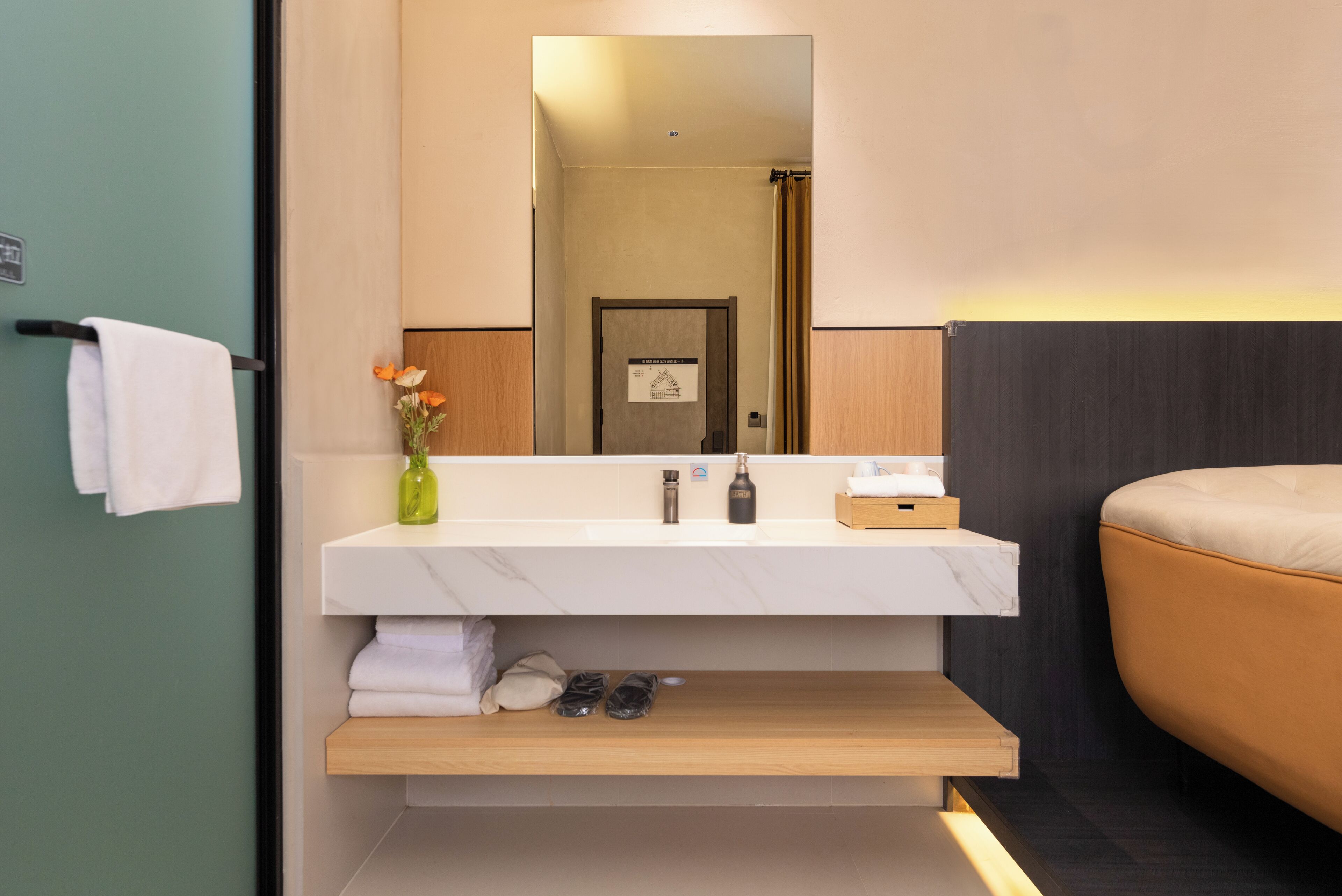Ein modernes Badezimmer mit einem Marmorwaschbecken, einem Spiegel, einem Handtuchhalter, einem Holzregal und einer beigen Badmatte.