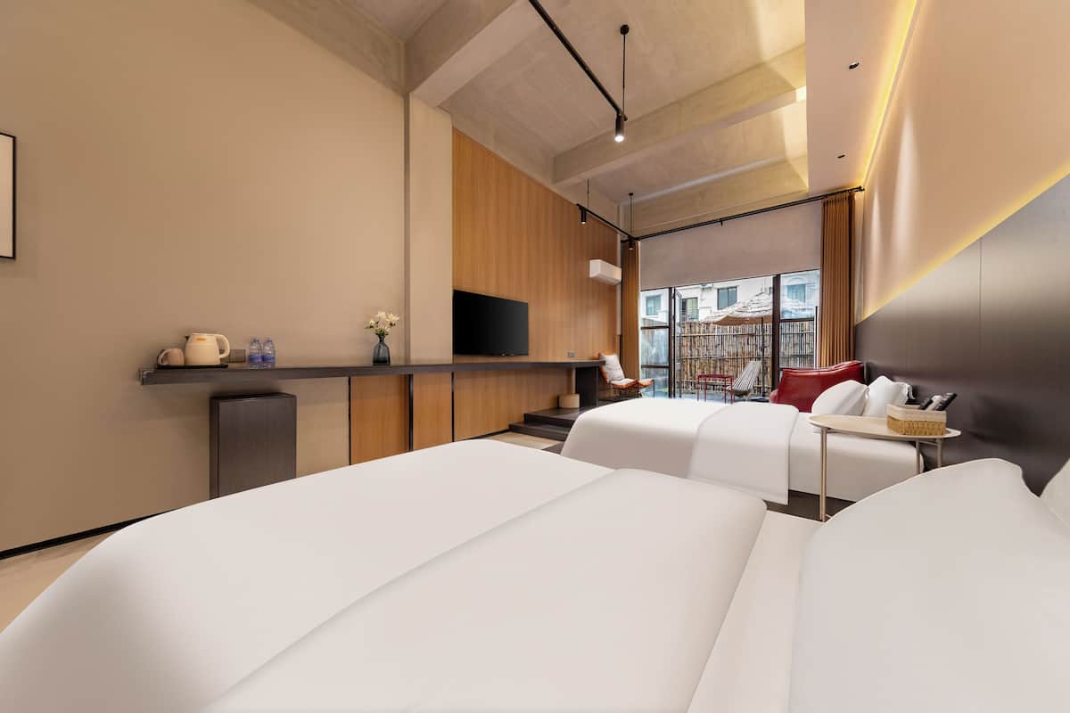 A modern hotel room with a flat-screen TV, a sofa, a small table, and a view of the outside.