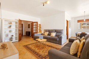 A living room with a grey sofa, a small round table, a patterned rug, and a wooden cabinet with decorative items. - Casa Tita, sea view, sleeps 6 (Lagos)