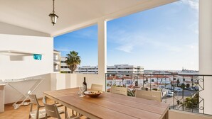 Een balkon met een eettafel, stoelen en uitzicht op een stadslandschap.