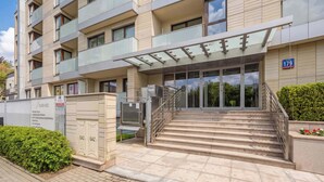 A modern building with a glass entrance, a staircase, and a sign with the number 179. - Stylish Apartment with a Private Garden | Air Conditioning (Warszawa)