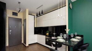 A modern kitchen with a dining area, black bar stools, and a clock on the wall. - Stylish Apartment with a Private Garden | Air Conditioning (Warszawa)