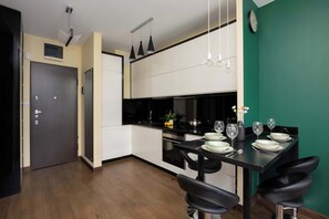 Eine moderne Küche mit Essbereich, schwarzen Barhocker und einer Wanduhr.