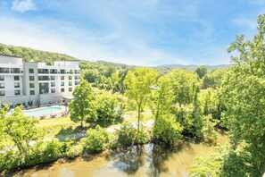 Ein modernes Hotel mit Schwimmbad, umgeben von üppiger Vegetation und einem Fluss.