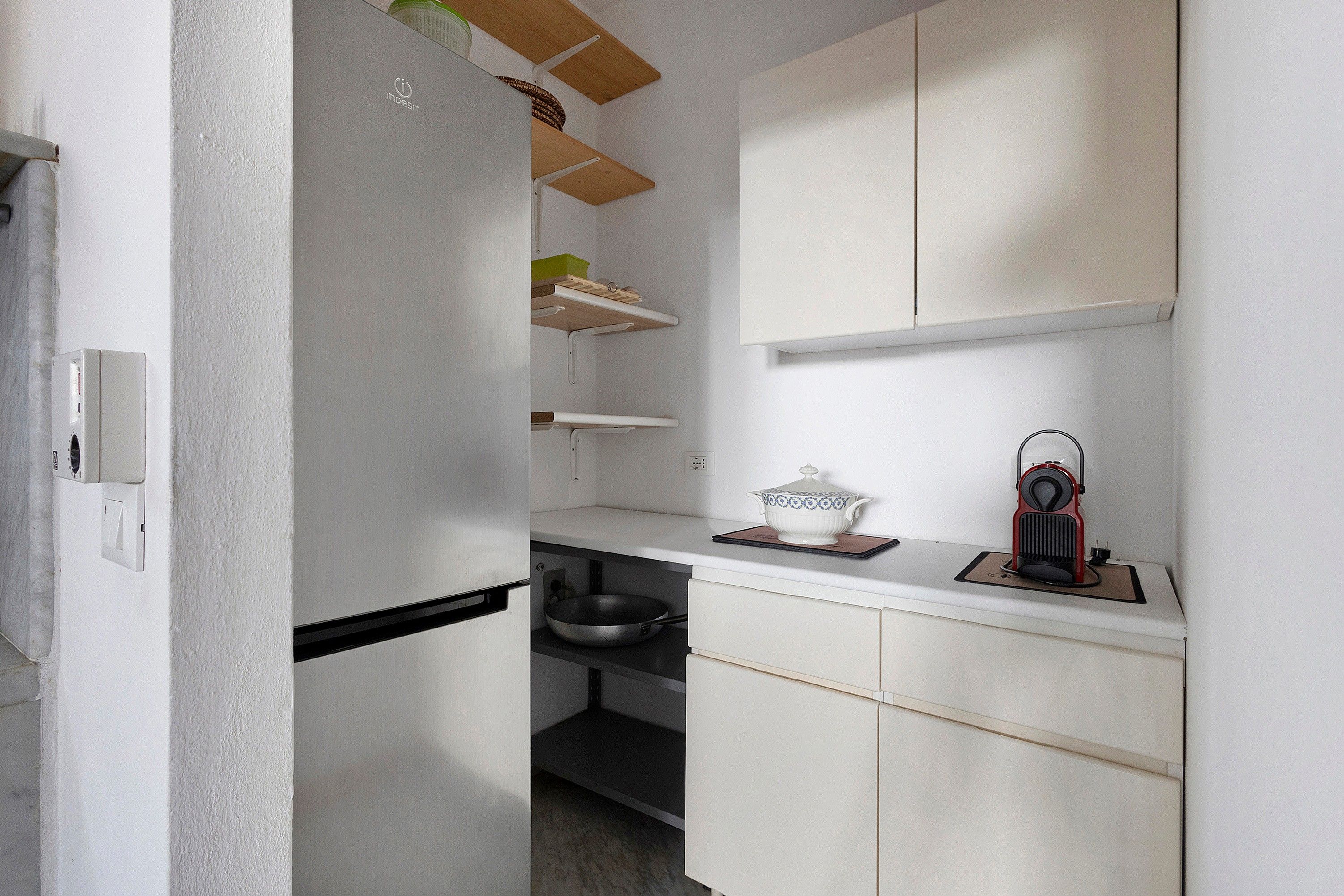 Una cucina con mobili bianchi, un piano di lavoro nero e un fornello.