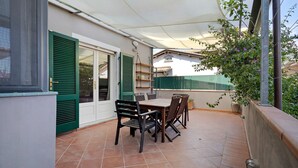 An outdoor patio with a table and chairs, a covered area, and a view of a building in the background. - Holiday Home 'La Colombaia Dei Pagliai' with Private Terrace, Private Garden and Wi-Fi (Ripa- Pozzi-Ponterosso)