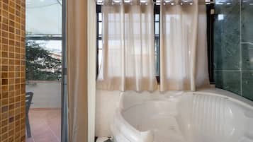 Ein Badezimmer mit einer Badewanne, einem Fenster mit Vorhängen und einem gefliesten Boden.