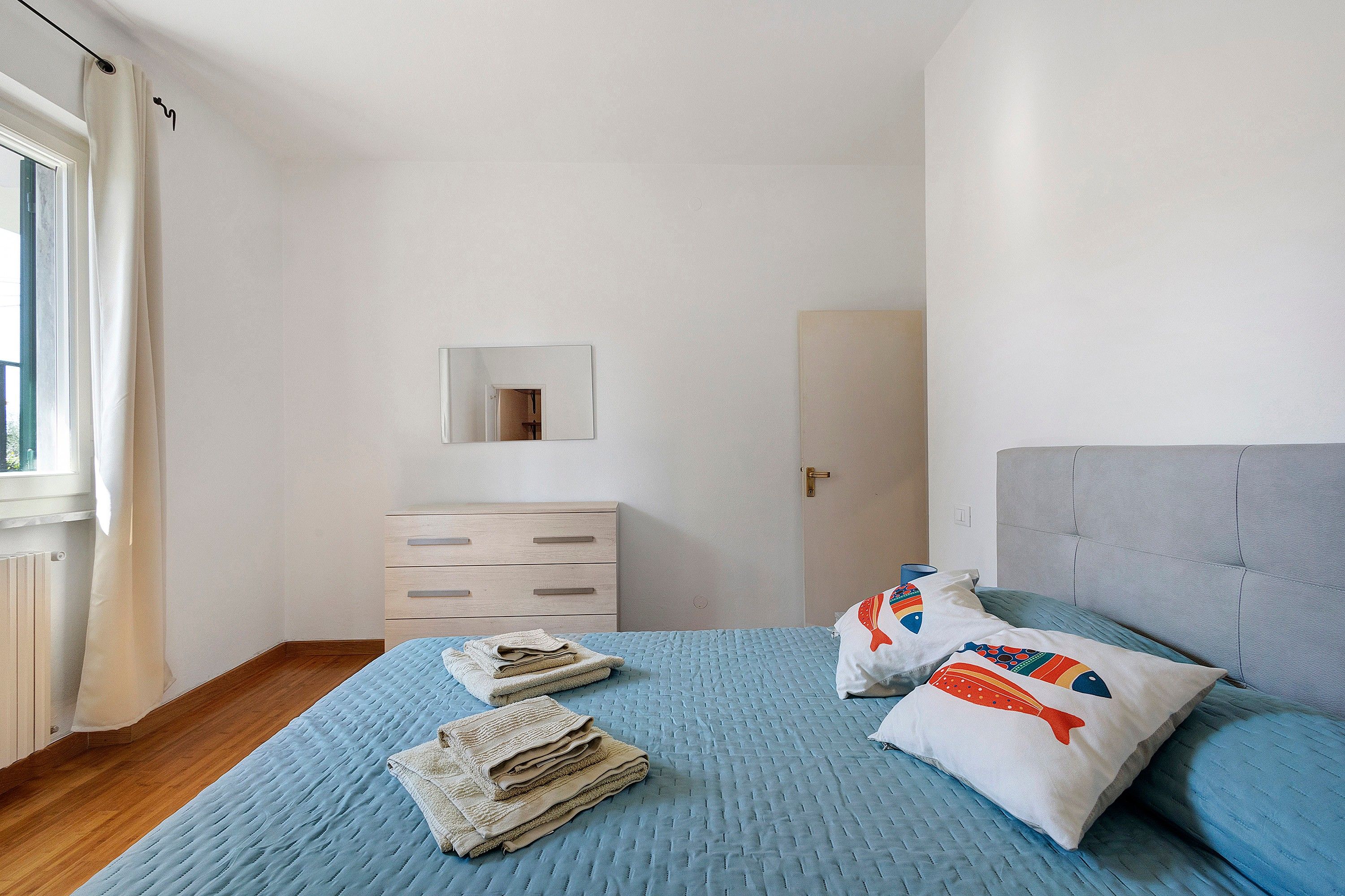 A bedroom with a bed, a dresser, a mirror, and a door.