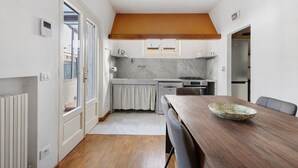 A compact kitchen with a dining area, a wooden table, and a view through the door. - Holiday Home 'La Colombaia Dei Pagliai' with Private Terrace, Private Garden and Wi-Fi (Ripa- Pozzi-Ponterosso)