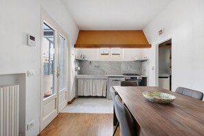 Una cocina compacta con una mesa de madera, horno empotrado y refrigerador.