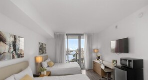 Ein Hotelzimmer mit Bett, Schreibtisch, Fernseher und Blick auf die Stadtlandschaft.