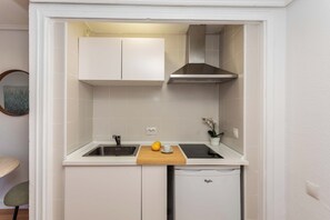 A compact kitchen with white cabinets, a built-in sink, a wooden cutting board, and a compact dishwasher. - This bright and modern apartment on Calle Julián Besteiro, in the heart of Tetuán, combines contemporary design, comfort, and functionality, creating a perfect space for extended stays in Madrid. (MADRID)