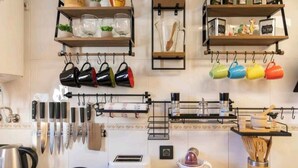 Une cuisine avec des tasses suspendues, des couteaux, un grille-pain et un extracteur de jus.