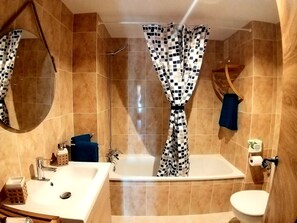 Un bagno con vasca, lavandino, WC e tenda da doccia.