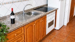 Une cuisine avec des meubles en bois, un évier en acier inoxydable, un réfrigérateur blanc et une cuisinière.