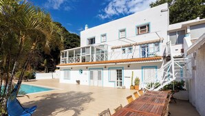 A white building with a pool, wooden deck, and outdoor seating area. - Home2Book Papaya Loft & Pool View (Santa Cruz de Tenerife)