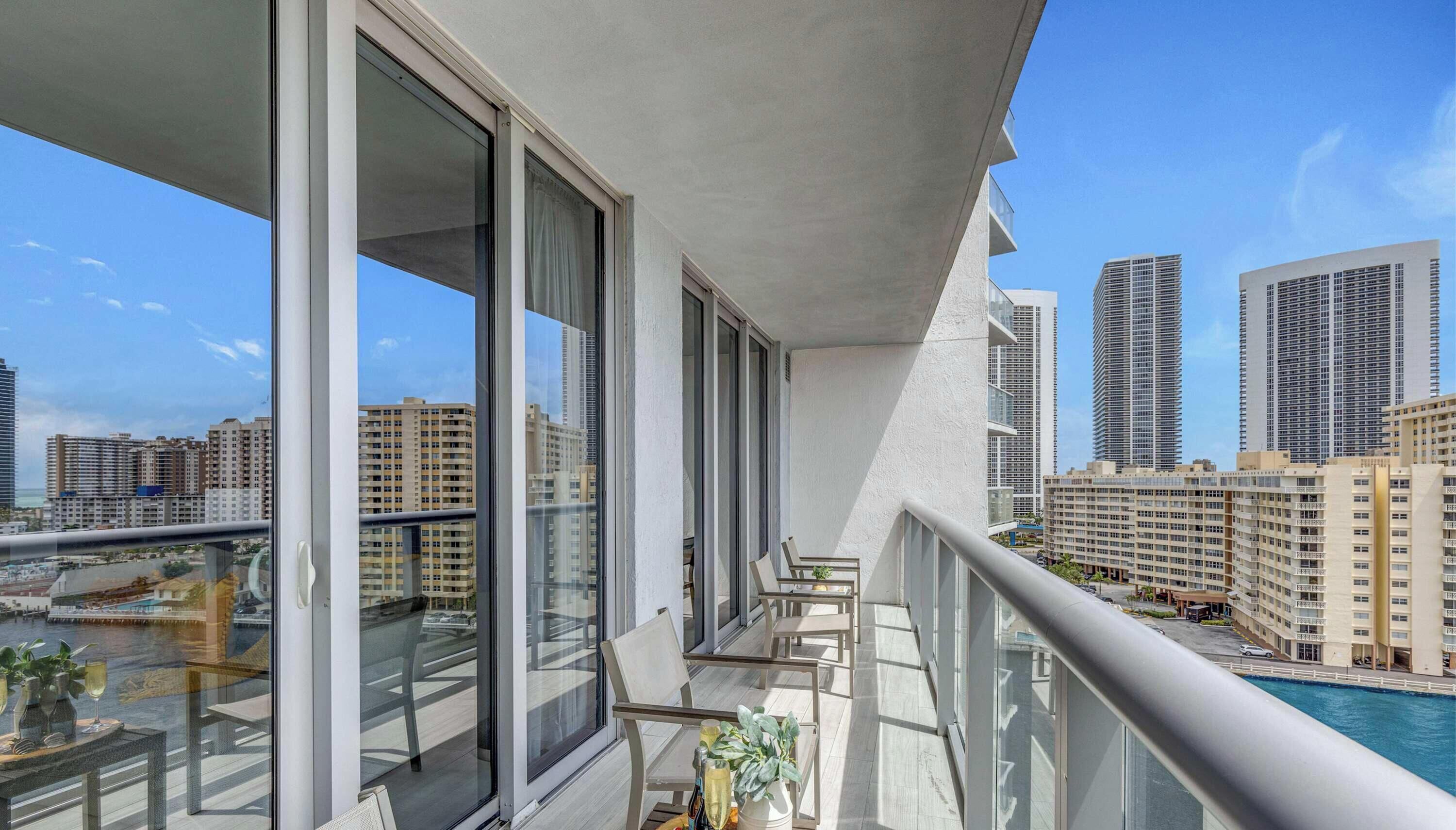 A balcony with a city view, large windows, and a poolside area.