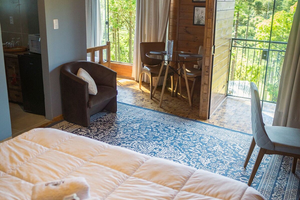 Un dormitorio con cama, una silla, una mesita y un balcón con vistas.