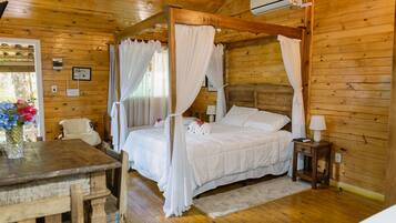 Quarto de cabana de madeira com uma cama de dossel, uma mesinha e uma cadeira.