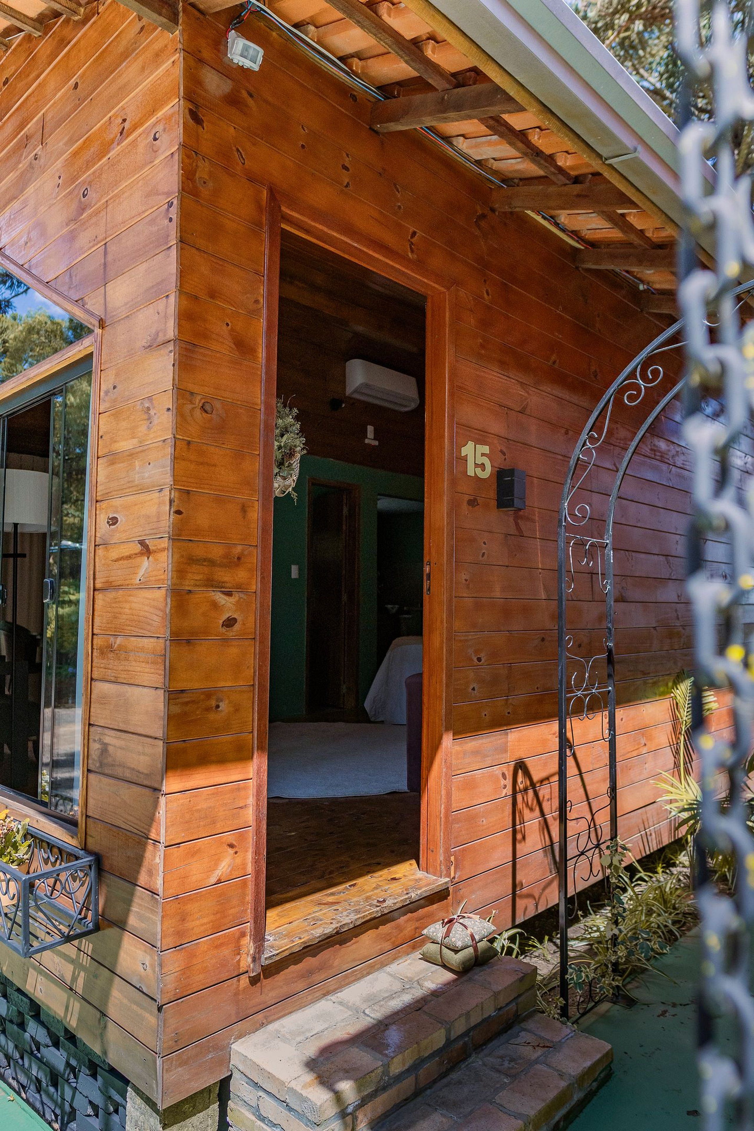 Uma cabana de madeira com o número 15 na parede, uma porta que dá para o interior e uma pequena varanda.