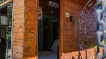 Uma cabana de madeira com o número 15 na parede, uma porta que dá para o interior e uma pequena varanda.