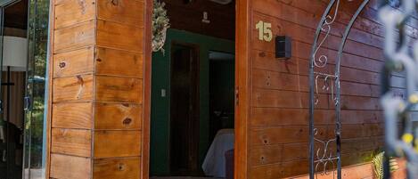 A wooden cabin with a number '15' on the wall, a door leading inside, and a small porch area.