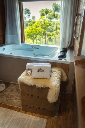 A bathroom with a bathtub, a fluffy towel, and a bottle of shampoo. - Rancho Nativo Pousada e Eventos (Curitibanos)