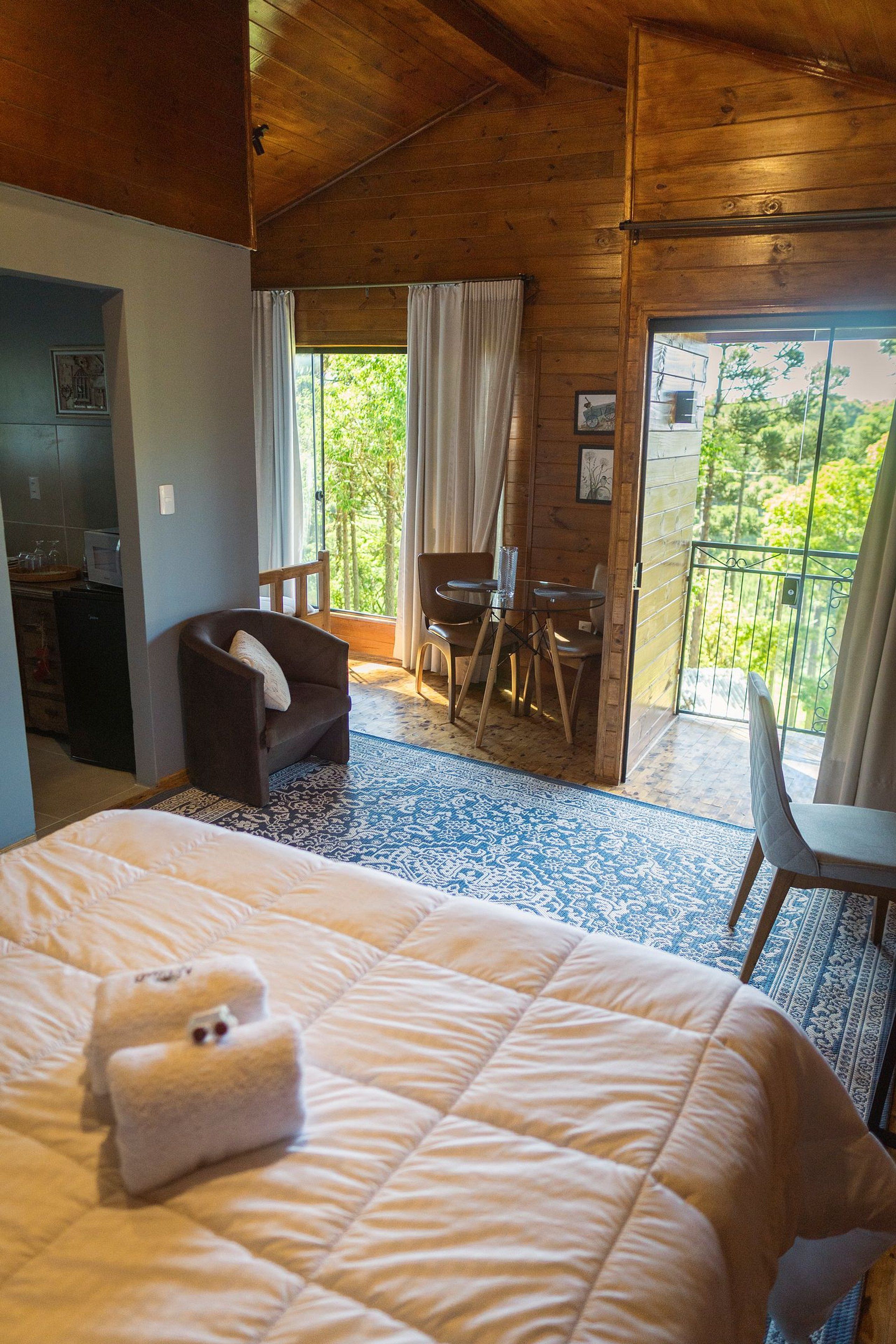 Un dormitorio con cama, una silla, una mesita y un balcón con vistas.
