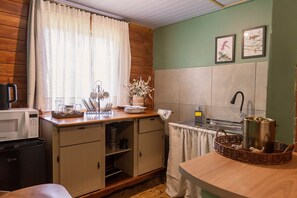A compact kitchen with a microwave, sink, and wooden cabinets.