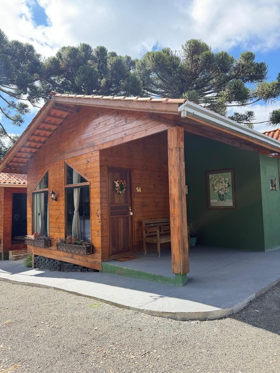 Una cabaña de madera con fachada verde, un porche y el número 14 en la puerta.