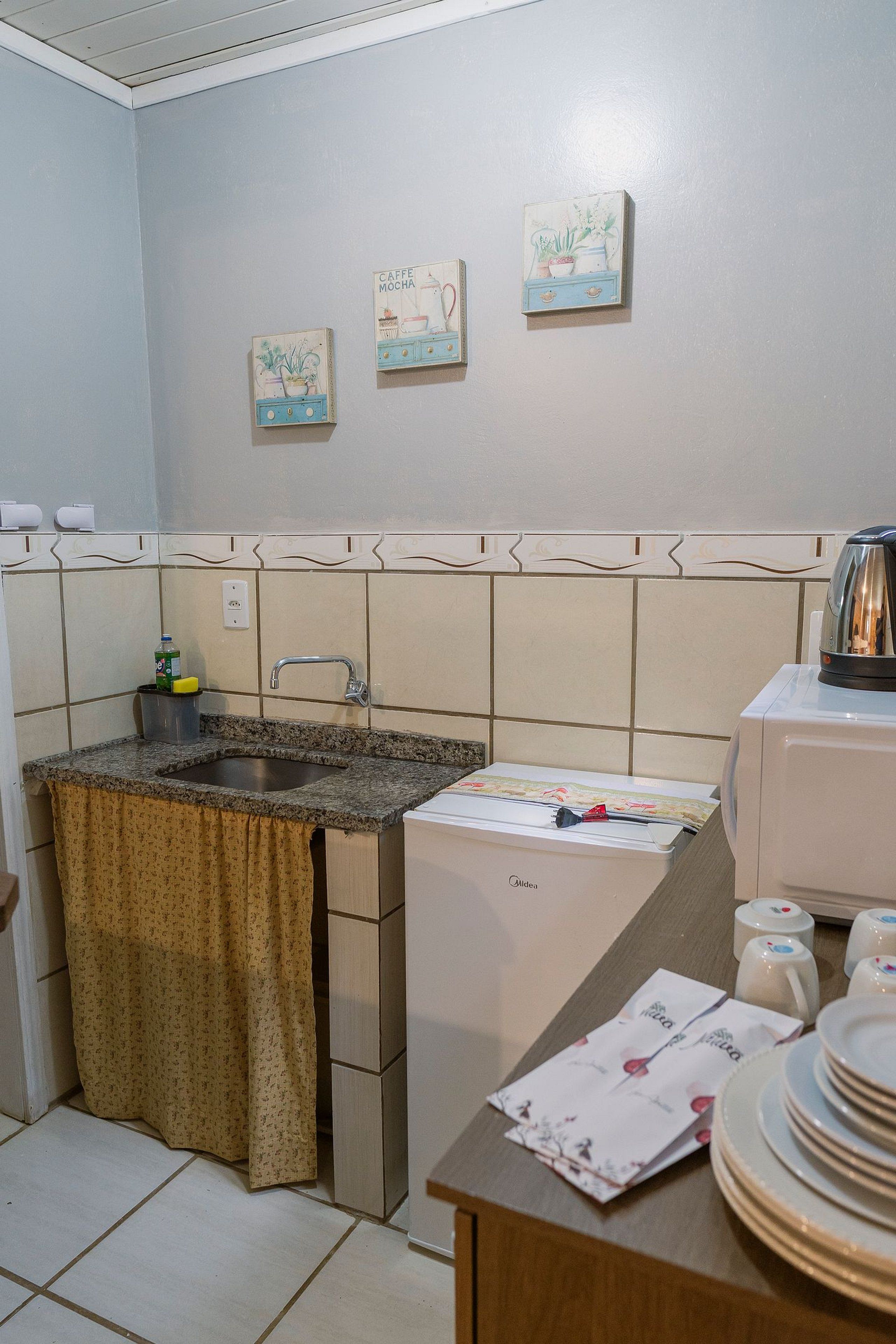 A kitchen with a sink, a coffee machine, and a refrigerator.