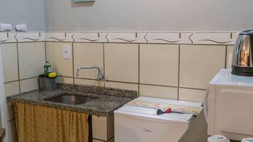 A kitchen with a sink, a coffee machine, and a refrigerator.