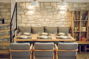 A dining area with a stone wall, wooden table, and cushioned chairs.