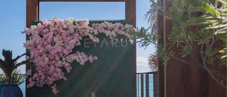 Une structure en bois sur laquelle est apposée une enseigne indiquant « ETARU », et qui est décorée de fleurs roses.