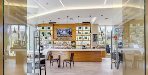 A modern bar area with a TV screen, wooden counter, and seating. - Stylish 1BR, Bay View Balcony, Resort & Beach (Hallandale Beach)