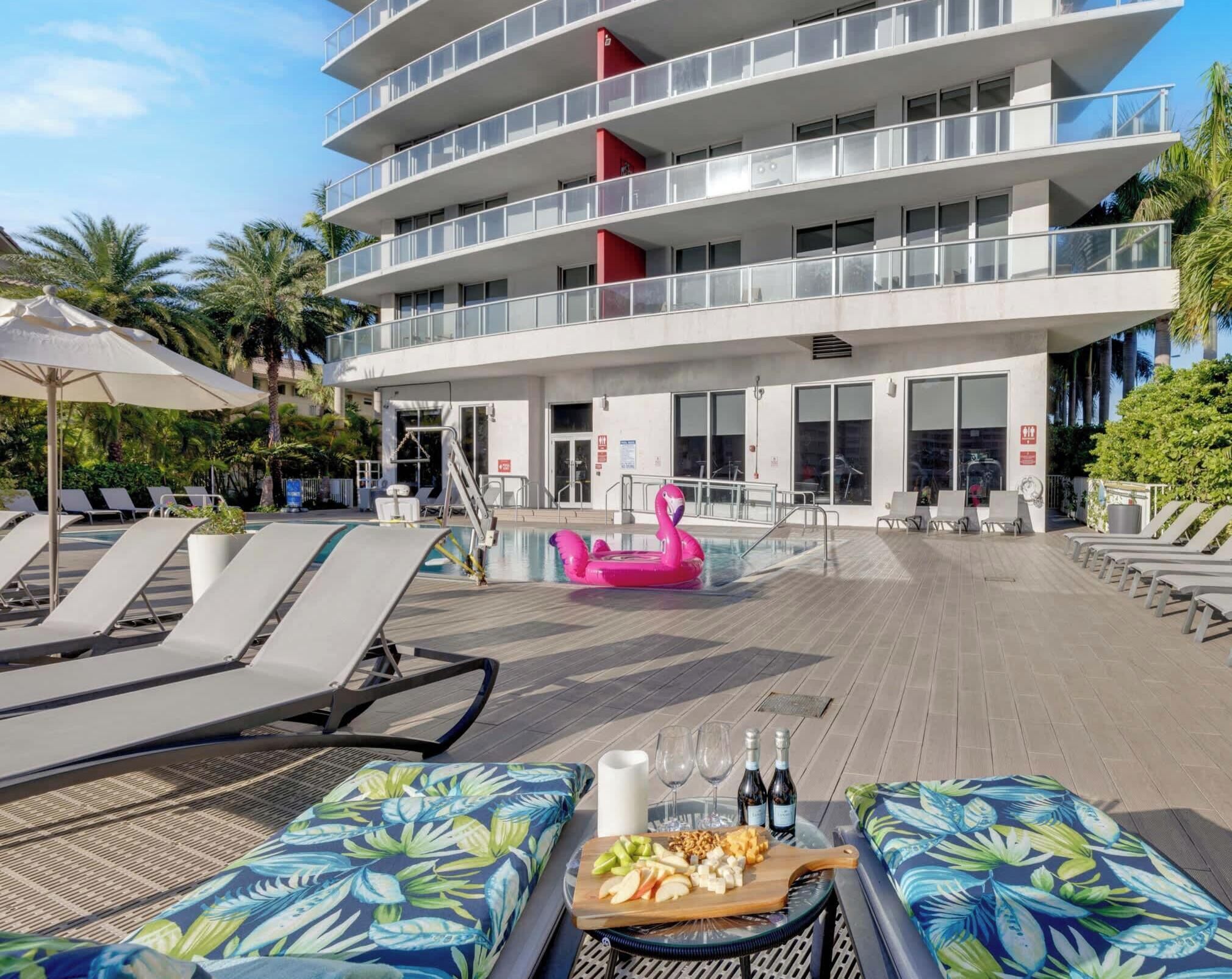 Een modern hotel met een zwembad, ligbedden en een eetgedeelte met eten en drinken.
