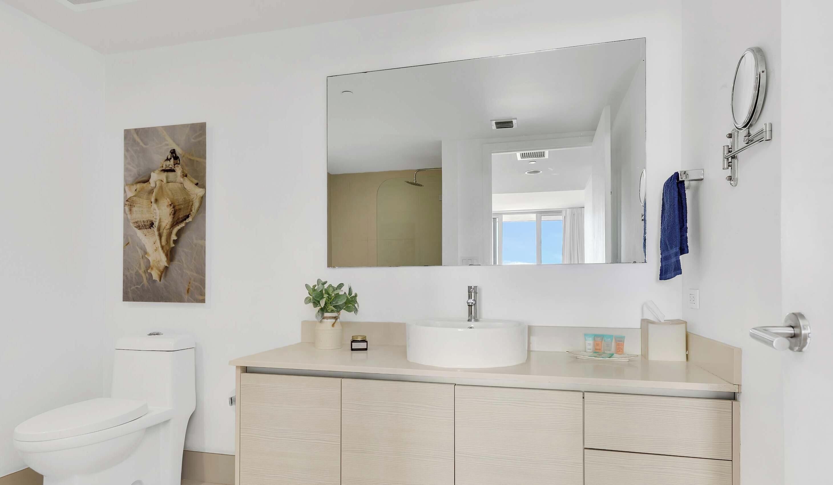 Ein modernes Badezimmer mit Toilette, Waschbecken, Spiegel und Dusche.