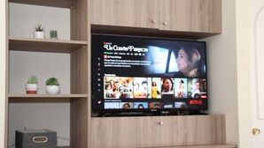 A flat-screen TV mounted on a wooden cabinet with shelves above it.