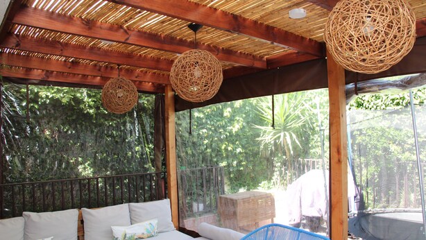 An outdoor seating area with a wooden bench, a blue chair, and a white sofa with cushions.