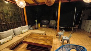 An outdoor patio with a wooden table, blue chair, and a sofa.