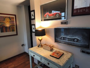 A room with a wooden table, a lamp, framed artwork, and a map on the wall.