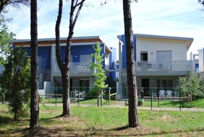 A modern building with a flat roof, large windows, and a balcony. - Cozy and Quiet Residence of Townhouses in Bibione (San Michele al Tagliamento)