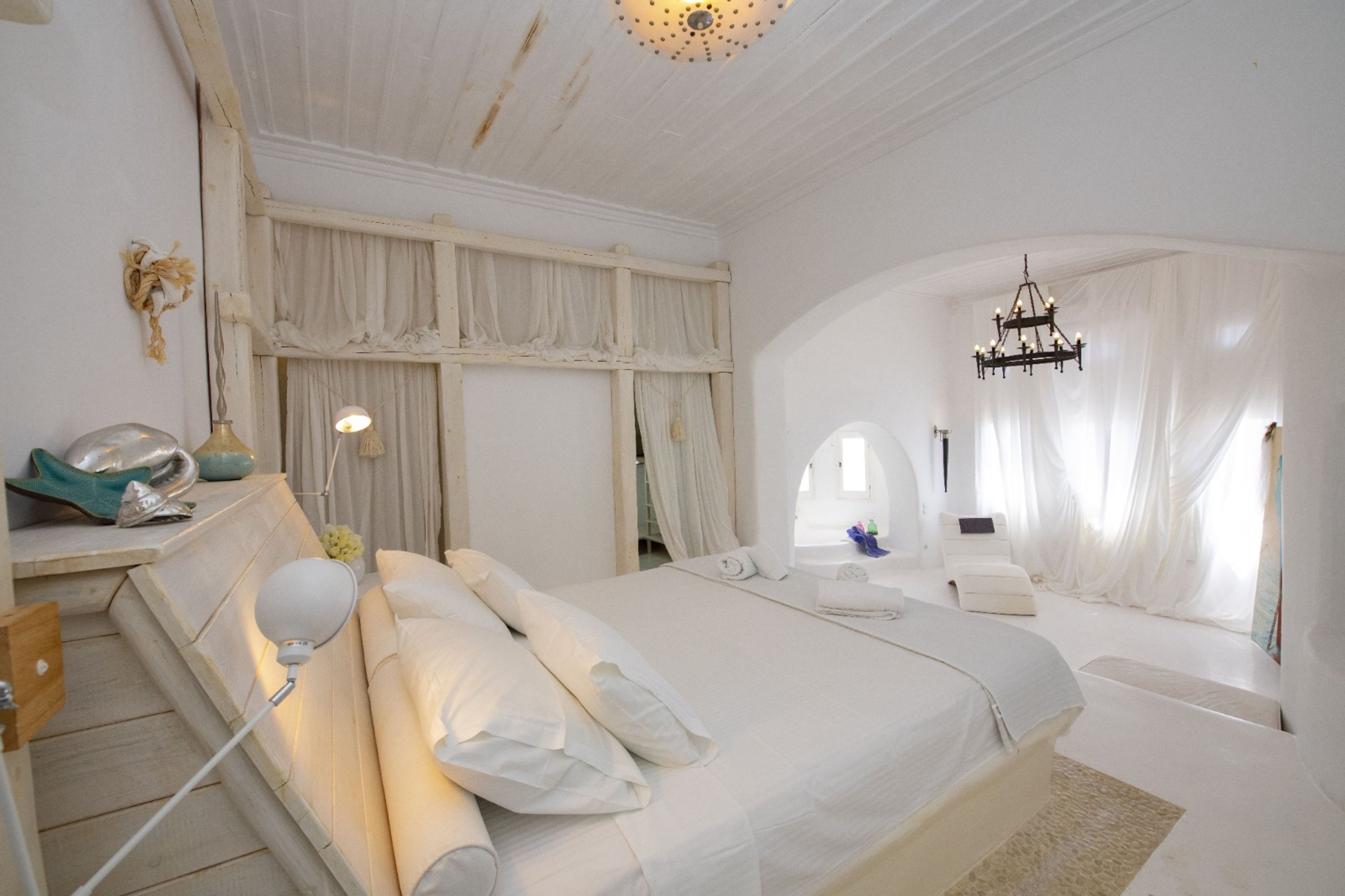 Une chambre spacieuse avec un grand lit, un lustre et une vue sur la mer.