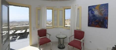A room with a balcony, a table with chairs, and a painting on the wall.