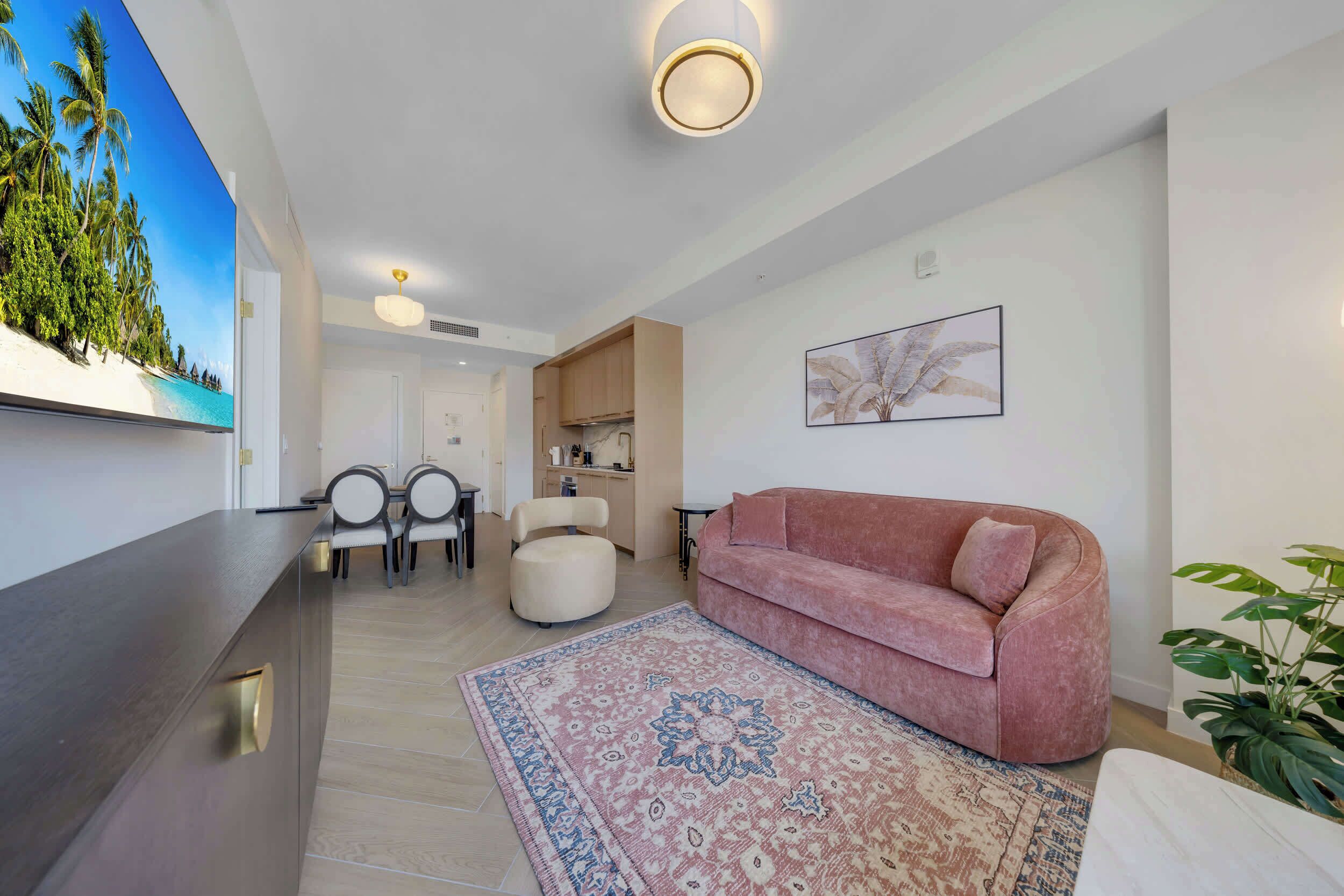 A modern living room with a sofa, a coffee table, a TV, and a dining area with chairs and a table.