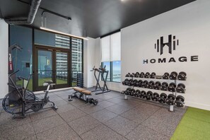 Ein Fitnessraum mit Trainingsgeräten, einer Bank und einem an der Wand befestigten Hantelständer.