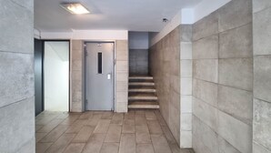 Un pasillo con una puerta, una escalera y paredes con baldosas.