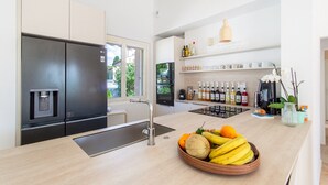 A modern kitchen with a built-in refrigerator, a coffee station, and a fruit bowl on the counter.